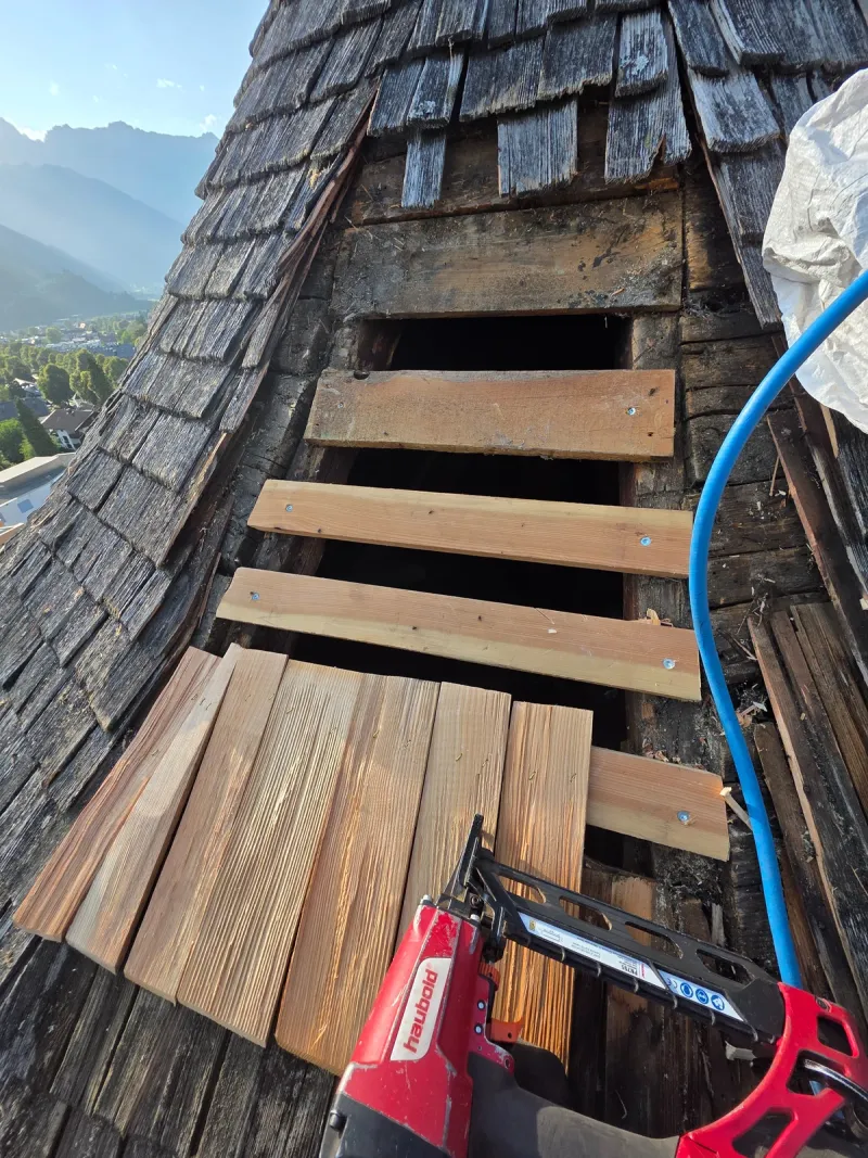 Geöffnete Schindeldeckung mit sichtbarer Unterkonstruktion und neuen Holzschindeln