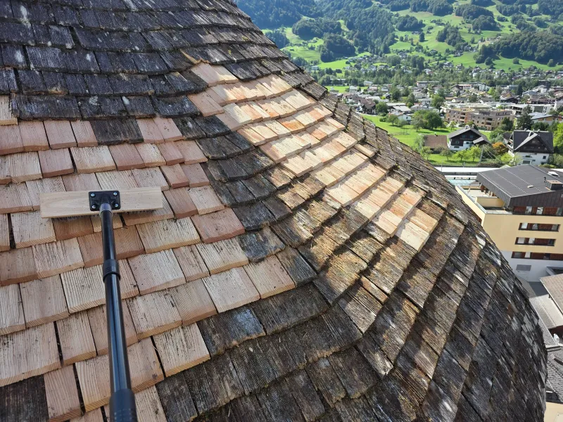 Helle neue Holzschindeln neben dunkler bestehender Schindeldeckung